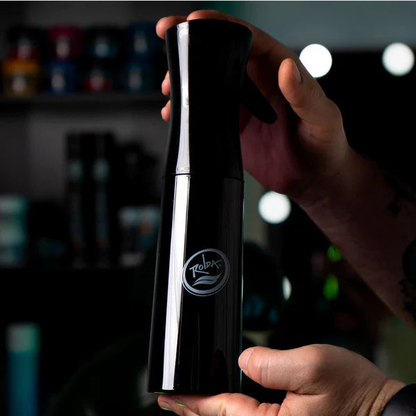 Person holding a black pepper grinder with a blurred background