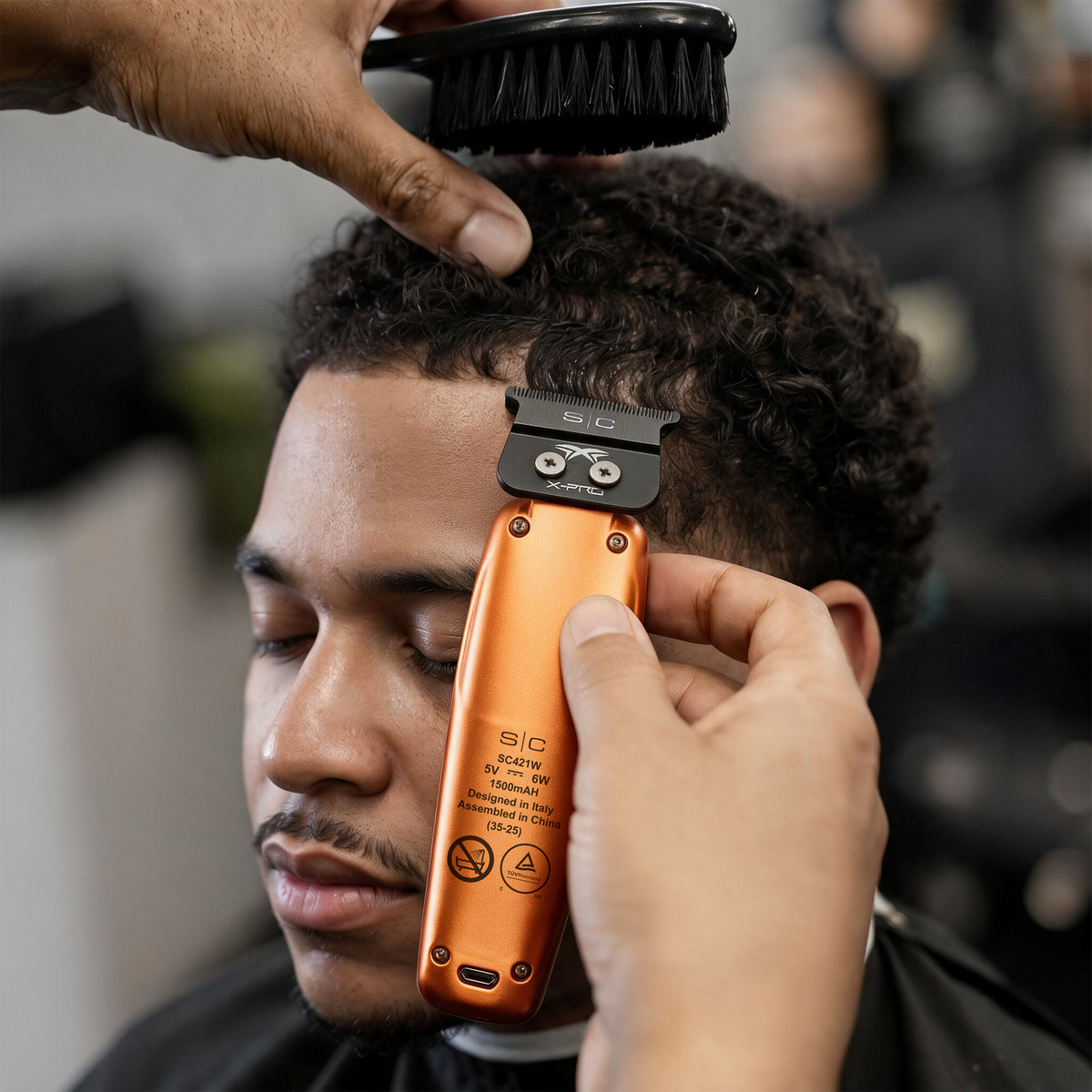 Barber using StyleCraft Saber SC421O orange trimmer on a client